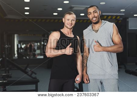 Muscular Confident Men Showing Thumbs Up. Successful Multiethnic Fitness Instructors Smiling At Came