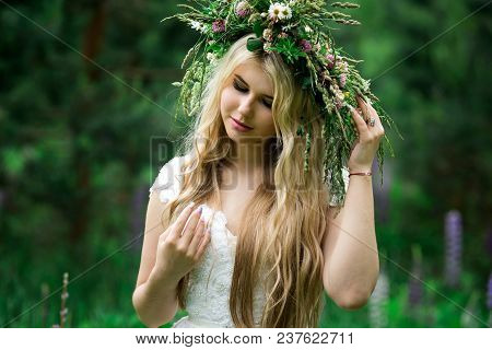 Romantic Girl In A Wreath Of Wild Flowers In A Field. Summer Life. Beauty.