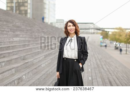 Caucasian Businesslady Standing On Stairs Outside In High Buildings Background. Concept Of Professio