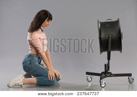 Young Sexy Female Model Posing With Working Wind Machine On Grey Background