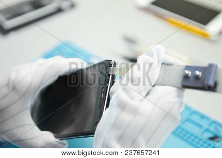 Cropped View Of Man's Hands In Antistatic Gloves Disassembling Smartphone Using Special Tools. Unkno