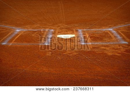 Baseball homeplate with batter box chalk lines in brown clay dirt
