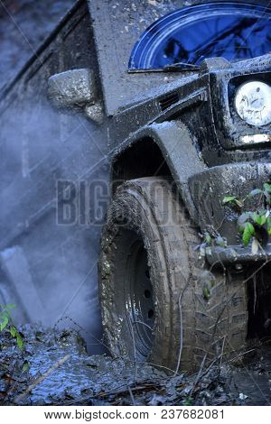Part Of Suv Stuck In Dirt, Close Up. Dirty Offroad Tire Covered With Mud. Wheel With Cloud Of Smoke,