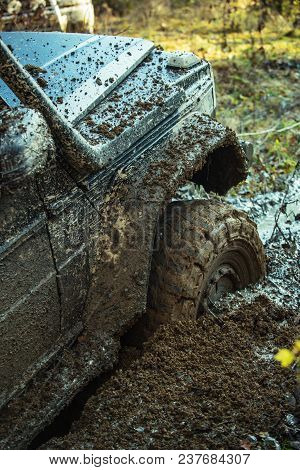 Fragment Of Car Stuck In Dirt, Close Up. Dangerous Expedition Concept. Offroad Tire Covered With Mud