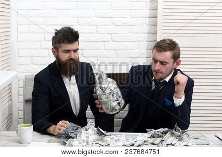 Business Partners, Businessmen At Meeting In Office. Colleagues On Thoughtfull Face With Jar Full Of