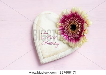 White Painted Wooden Heart Shape And A Flower Head On A Bright Pink Background, German Text Alles Li