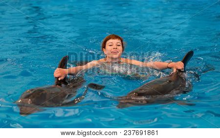Young Happy Girl Swimming With Dolphin