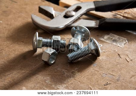 Nuts And Bolts On Workbench With Pliers In Background