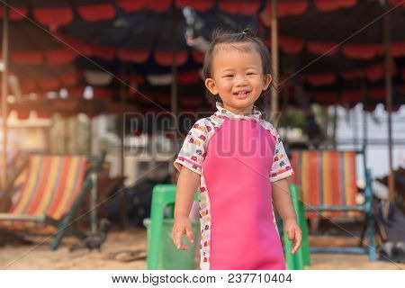 Asian Cute Baby Girl Smiling On The Beach Background, Child Swimsuit Ready To The Sea, Portrait Chil
