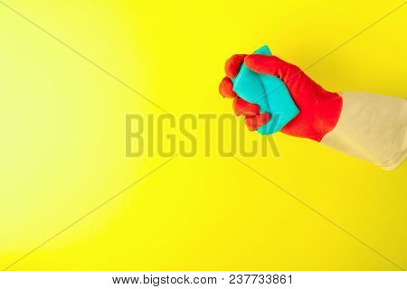 Hand Holding A Sponge For Dishes On Pastel Yellow Background