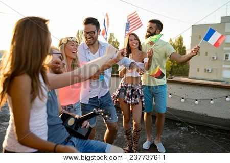 Group Of People Holding National Flags And Having Fun On Rooftop