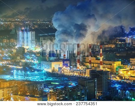 Power plant emitting smoke from smokestacks over night city skyline. Moscow, Russia