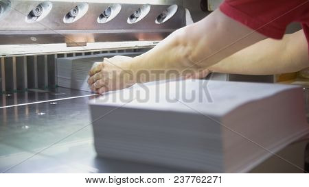 Hands Of Worker Takes Away Reams Of Paper From Cutting Maschine In The Print House, Close Up