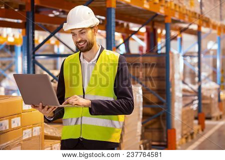Large Scale Distribution. Professional Delivery Manager Using Laptop For His Work While Dealing With