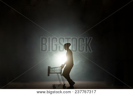 Portrait Of A Man Pushing An Empty Shopping Cart Isolated On Black Background. After Shopping. Night