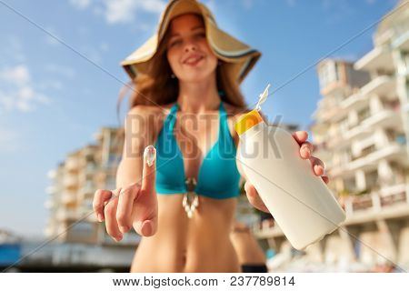 Closeup Of Smiling Caucasian Woman Showing Sunscreen Oil Bottle And Using Suntan Cream Smear On Fing