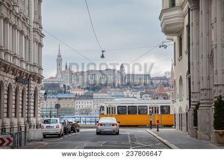 Budapest, Hungary - April 7, 2018: Buda Castle Seen From Pest With A Tram And A Car Passing In Front