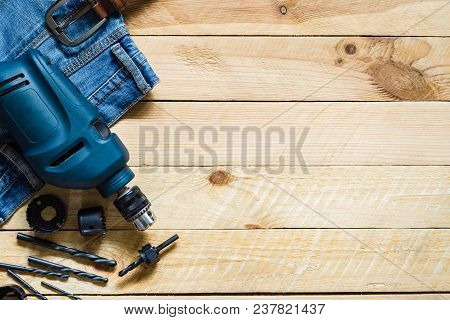 Blue Electric Power Drill With Set Of Bit And Blue Jeans On Gruge Wooden  Plank Background Top View 