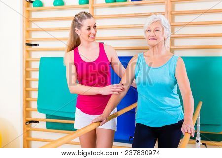 Walking Rehab in with senior woman, trainer guiding her to remobilization