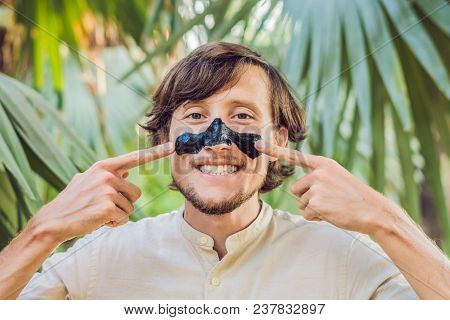 Happy Man With Black Mask On The Face. Photo Man Receiving Spa Treatments. Beauty Skin Care Concept.