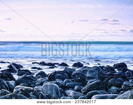 Blue Sunset At Rocky Coast Of Sea. Slow Shutter Speed For Smooth Water Level And Dreamy Effect