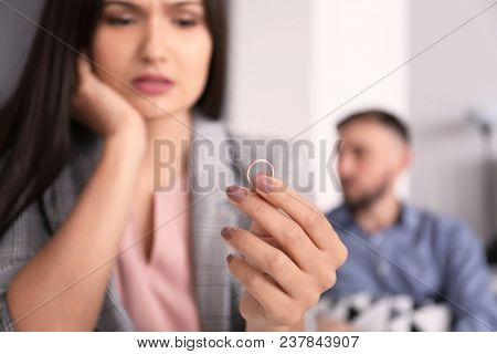 Sad woman with wedding ring and her husband on background. Time to visit family psychologist