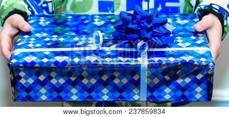 Bright Blue Gift Box With Silber Ribbon Bow In Child's Hands