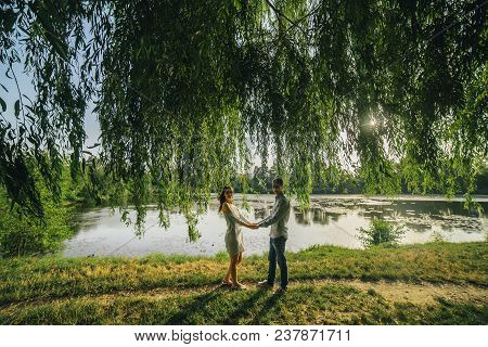 Happy Loving Couple Stay And Hugging At Park Background Lake. Young Cople That Is About To Kiss. Sum