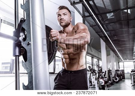 Muscular Bodybuilder Guy Doing Exercises With Dumbbell  On Multipress In Gym