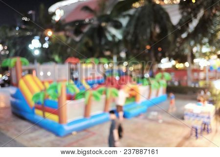 Blurred A Children Playground In Outdoor Space At The Night Market And An Urban Fair With People Wal