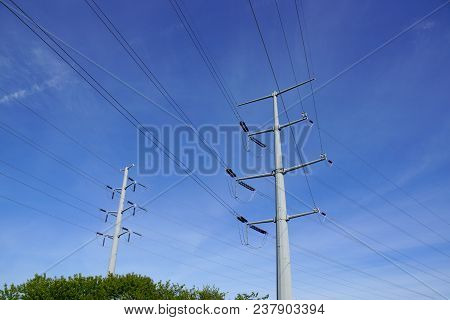 Two Metal Power Line Poles Above The Trees In Maine.