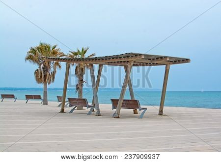 Wooden Shade Structure With Seats, Blue Mediterranean Sea On An Overcast Day And Horizon In Molinar,