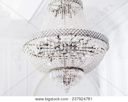Large Many-tier Chandelier With Glass Pendants. Interior Element With Crystal Details In White Room.