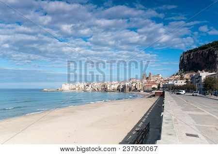 Cefalu, Sicily. Ligurian Sea and sunny old town-medieval sicilian city. Province of Palermo, Italy. Summertime outdoors horizontal image. Wide angle view with cloudy sky.