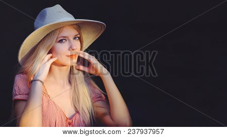 Beautiful Young Woman In Pink Dotted Summer Dress And Sun Hat Points To Copy Space, Looking At Camer