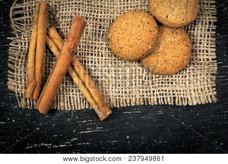 Oatmeal Cookies, Cinnamon On Burlap And Black Old Table.