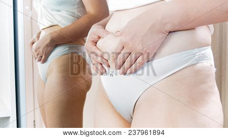 Woman Standing At Mirror And Holding Fat On Her Big Belly