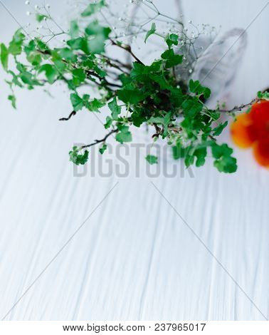 Branches With Green Leaves In A Basket On A Wooden Background.