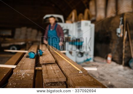 Carpenter with measuring tape measures boards