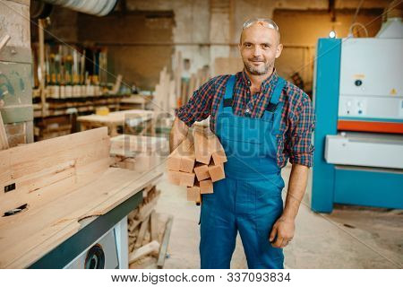 Carpenter holds stack of wooden beams, carpentry