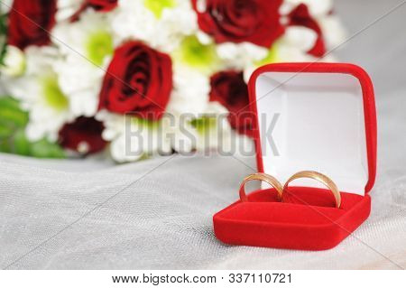 Wedding Gold Rings In A Red Box With Flowers In The Background