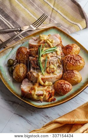 Sliced Honey Mustard Roast Pork Tenderloin With Baby Potatoes And Caperberry Garnish
