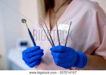 Dental Tools Set In Hands. Mouth Mirror, Periodontal Explorer Scaler, Tooth Extracting Forceps, Plie