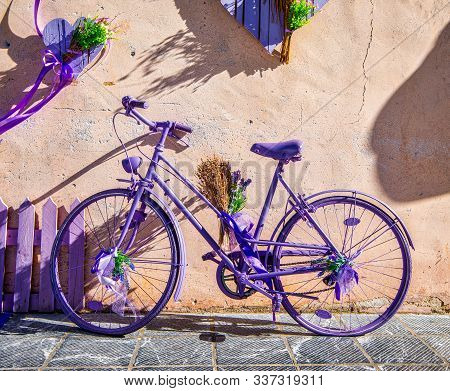 A Bicycle Painted Purple Lying Against A Wall