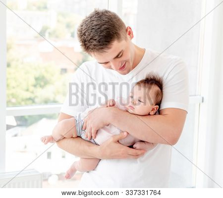 Father embracing infant near window
