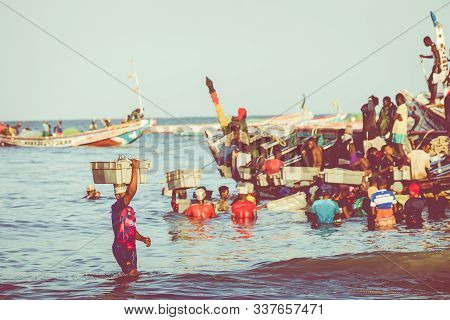 Tanji, The Gambia - November 21, 2019: Scene With Men And Women Carrying Fish From The Boats To The