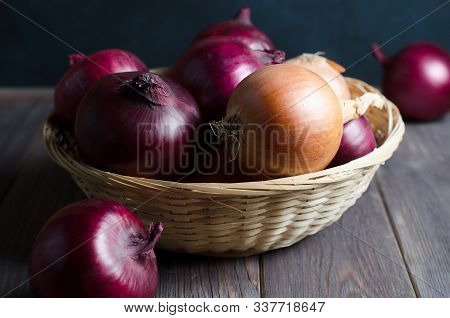 Red Onions In A Wicker Basket. Brown Wooden Background.