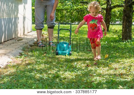 Cute Girl Lawn Mowing With Plastic Toy Mower.
