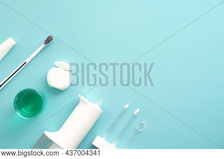 Flat Lay Composition With Dental Water Flosser, Toothbrush, Mouthwash, Dental Floss On Blue Backgrou