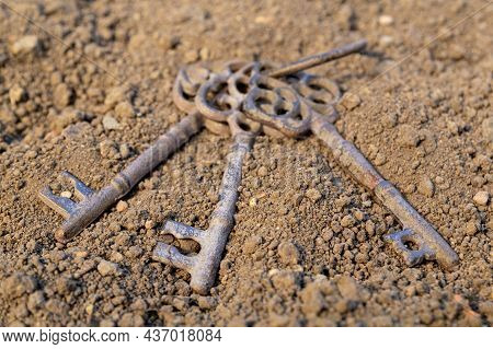 Old Rusty Key On Grunge Background. Antique Keys On The Rusty Ground Of Brown Color Background.middl